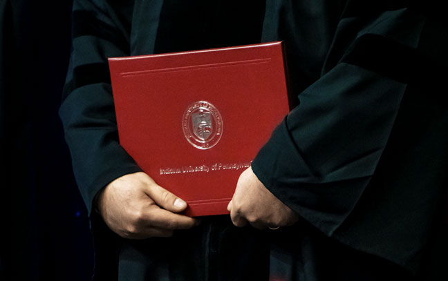 close up of a student holding a diploma at commencement