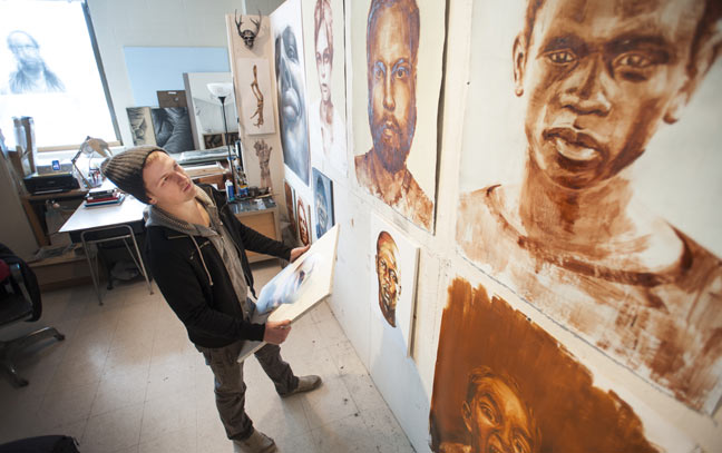 a student in an art gallery looking up at a wall of paintings