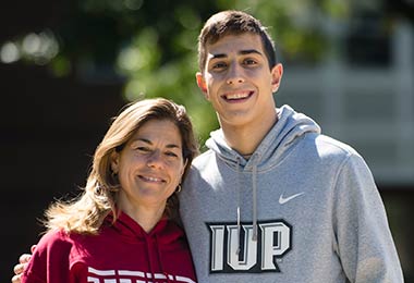 a young man and his mother smile together at the camera 