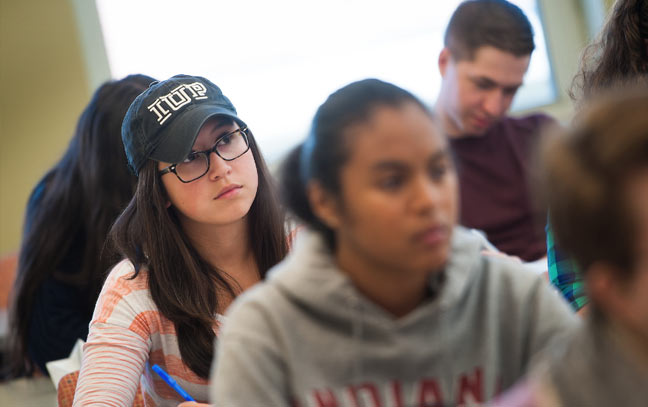 image of a female student in class in focus with others around her out of focus