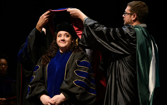 a student during a graduation ceremony having a sash placed on their robe