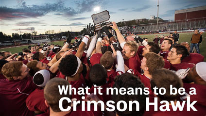 a group of football players celebrating in a group on a football field while all holding up a trophy in the shape of Pennsylvania