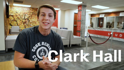 a young man standing in Clark Hall faces the camera mid discussion