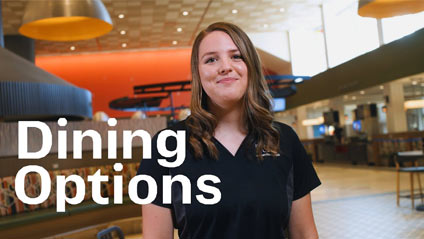 a young woman standing in a dining hall smiling at the camera