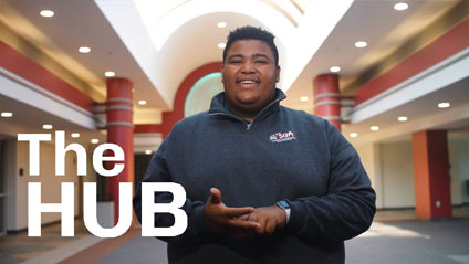 a young man stands facing the camera and smiling while in the IUP Hub