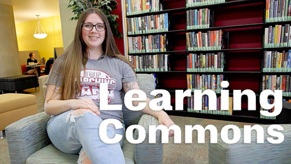 a young woman sitting in a chair in a library and smiling at the camera