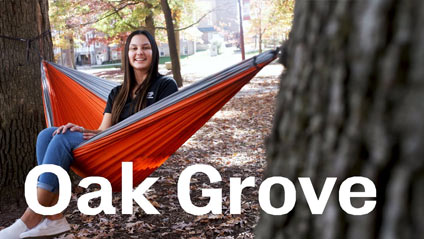 a young woman sitting in a hammock between two trees smiling at the camera