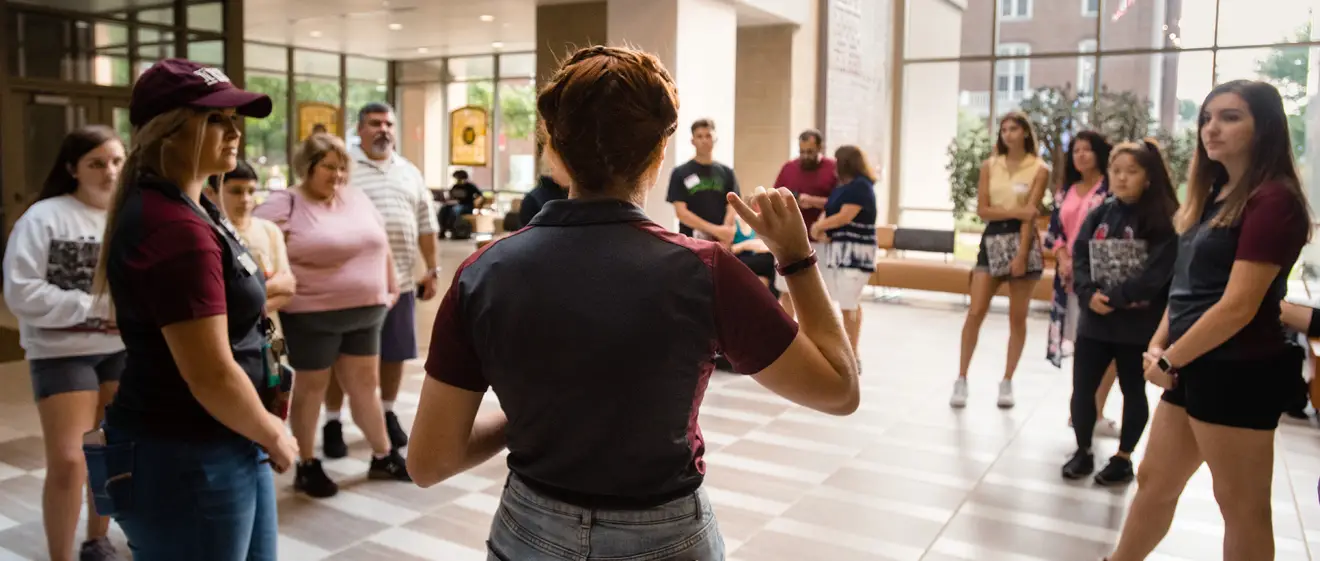 A student tour guide show a tour group around an academic building.