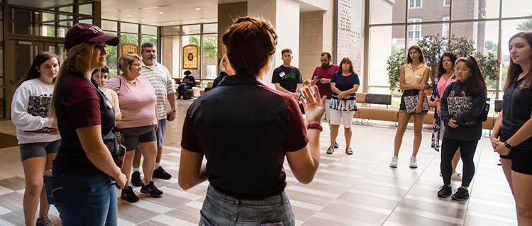 A student tour guide show a tour group around an academic building.