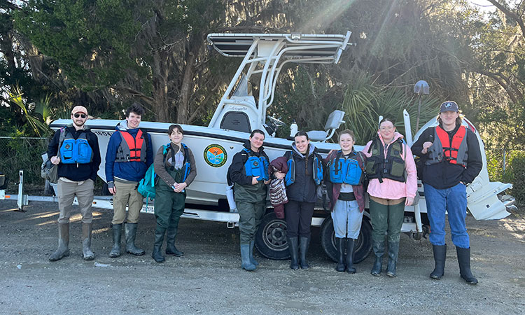 Group photo of students in front of boat.