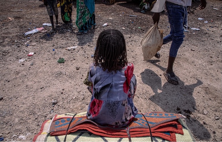 An image of a Eritrean refugee in Ethiopia sitting on their belongs.