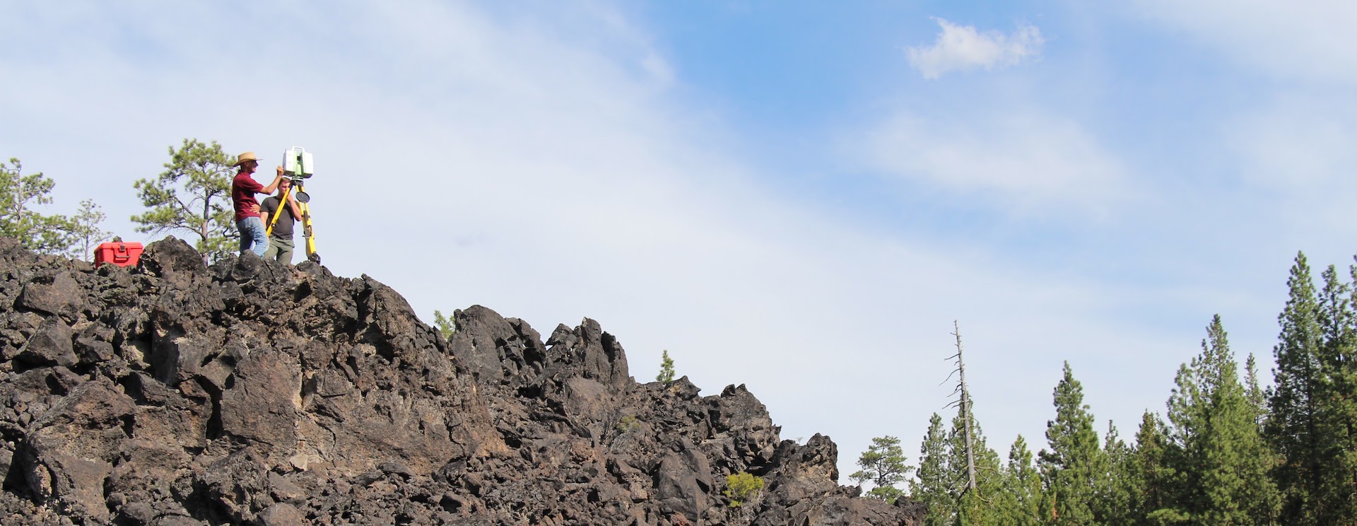 Students standing on top of ancient lava flow using LiDAR to map it.