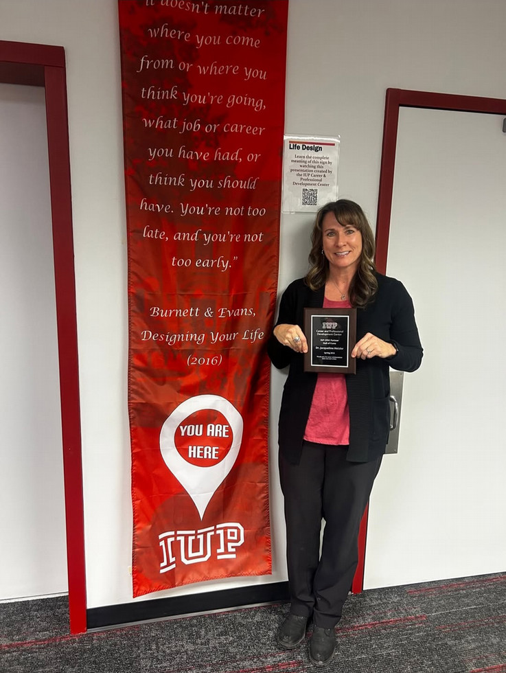 Jackie Heisler standing in front of a banner holding award from the CPDC.