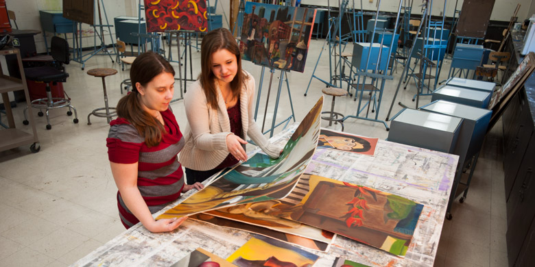 Student and faculty look at art on a table