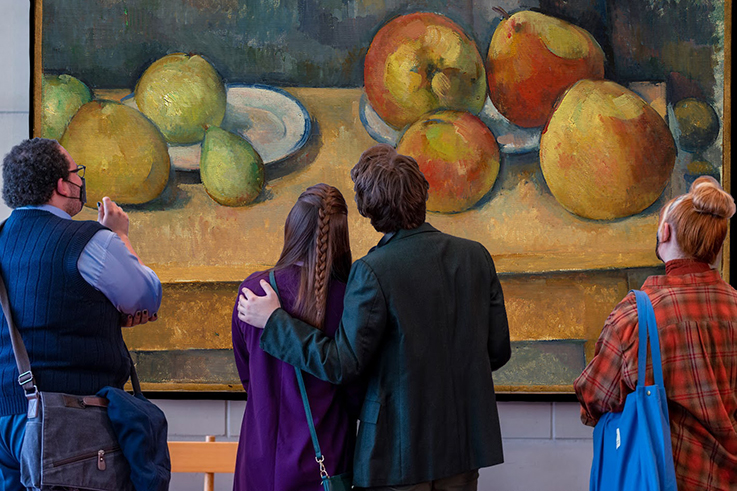 A scene from “Ordinary Days” with cast members looking at a painting on a wall