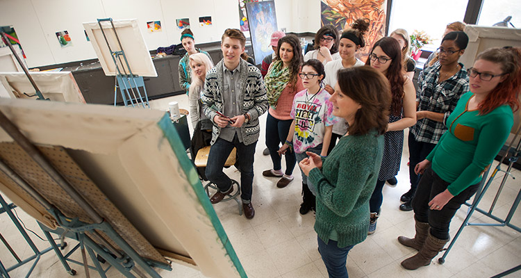 An art teacher instructs a group of students in a painting studio