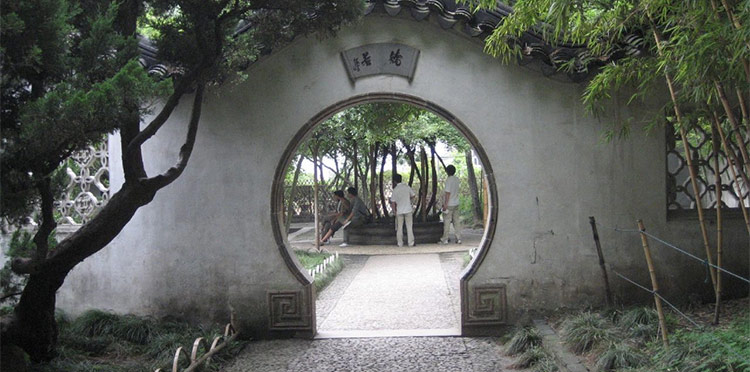 A keyhole-like door in a wall reveals people inside a garden