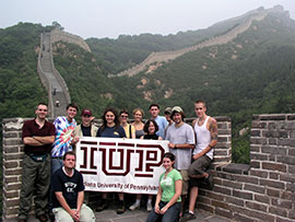 group of students holding an IUP banner stand on the great wall of China