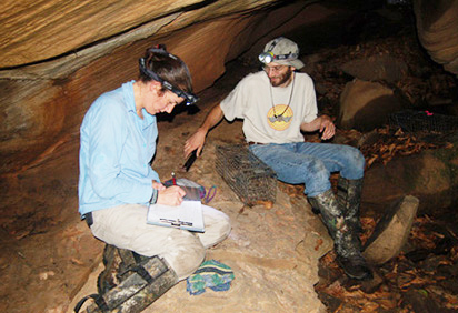 Student doing research in a cave with a professor
