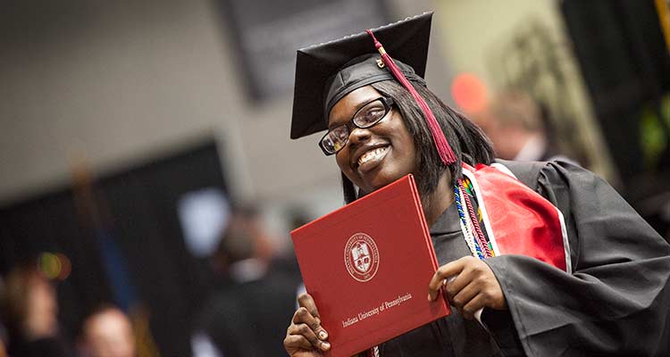 Graduate holding her diploma and smiling