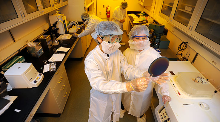 A physics student works with a professor in a lab