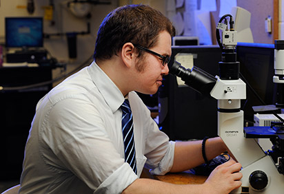 Physics student looking through microscope