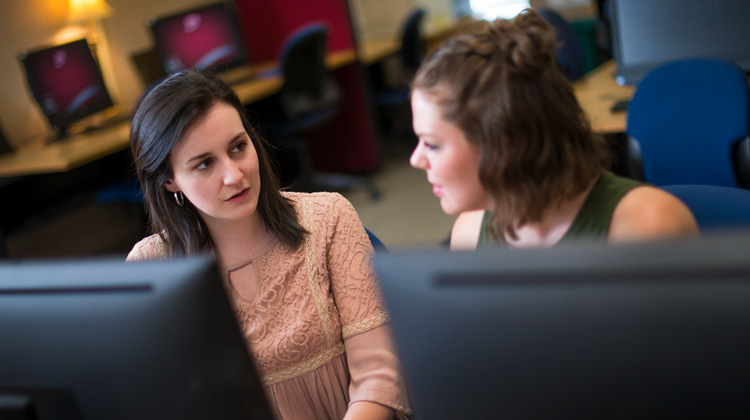 faculty member providing support to a student in a classroom setting