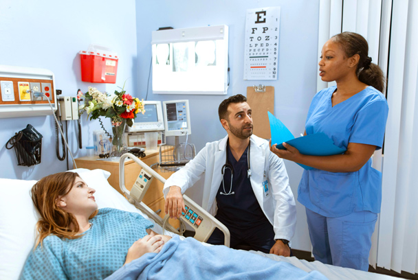 medical student and doctor standing at a patient's bedside in a hospital setting