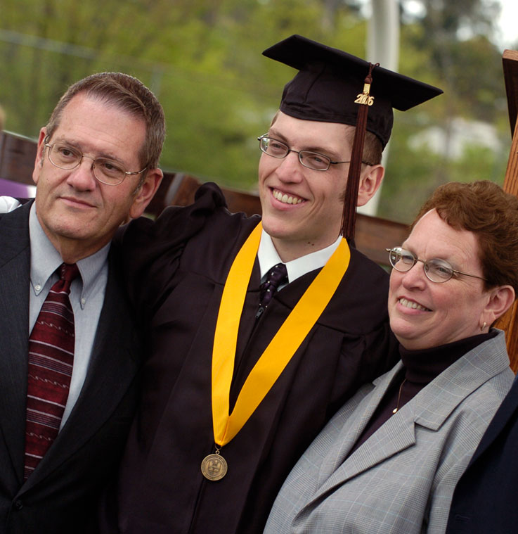 Graduating student with an honors medallion and his parents
