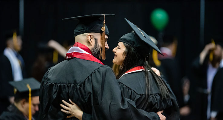 Two graduates embracing each other and smiling