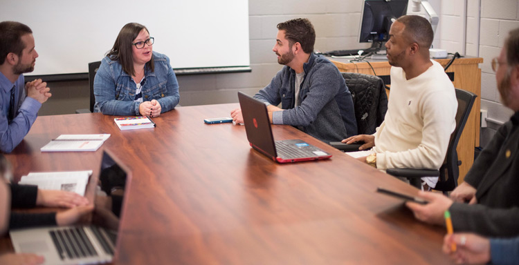 Grad Students and Professors sitting around a table.