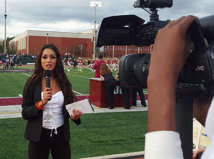 Student reporter on camera at a football game