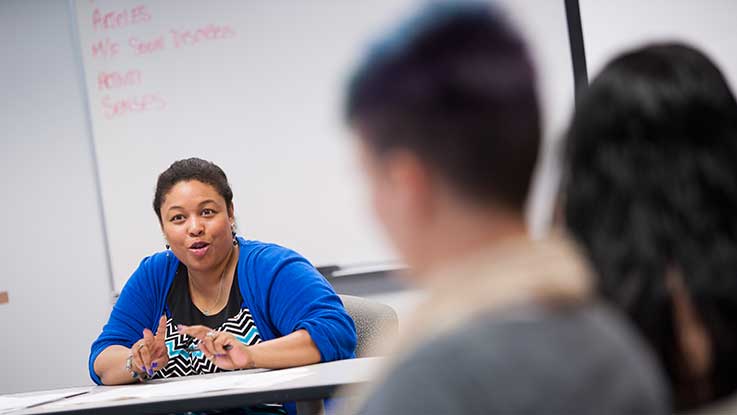 A professor talks with students in a classroom