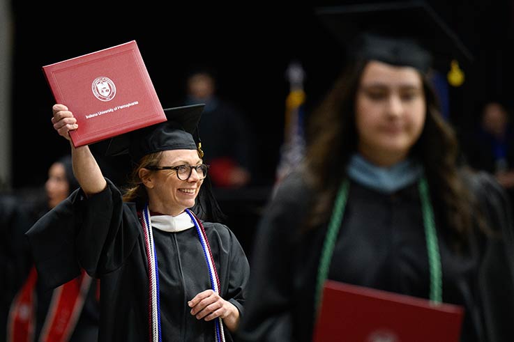 IUP graduate holding her diploma at commencement