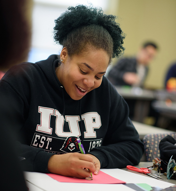 A student smiles as she looks at her notes in a class.
