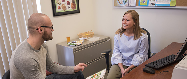 A dietitian-nutritionist program student engages in field work, reviewing a nutrition plan with a client. 