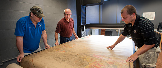 Students study a large mine map spread on a table
