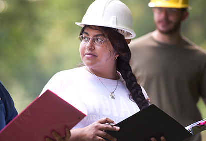 A student wearing a hard hat, out in the field for a geology class