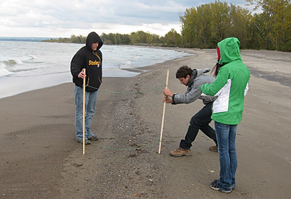 Students studying water drainage patterns on a beach