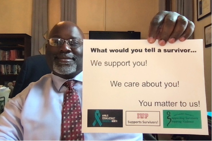 Tom Segar, vice president for Student Affairs, holding a sign saying "What would you tell a survivor? We support you! We care about you! You matter to us!"