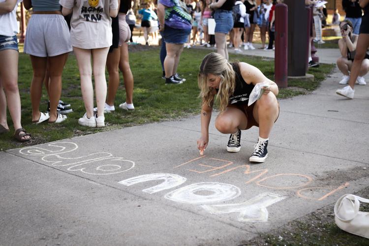 student chalking a message on the sidewalk