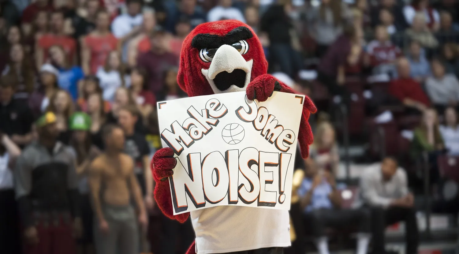 Norm holding a sign at a basketball game