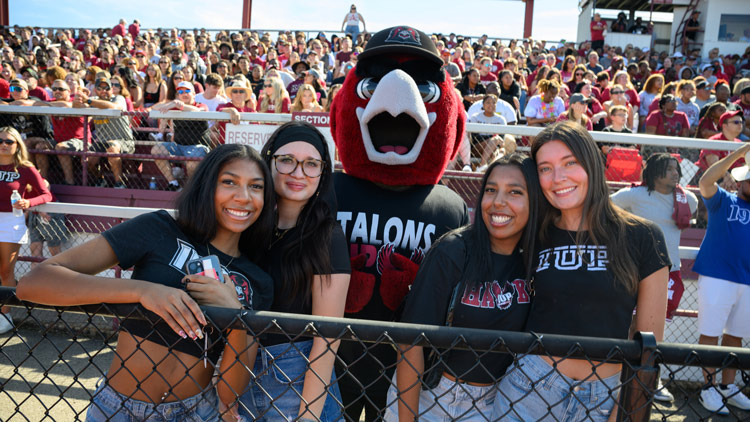 Mascot Norm posing with four female IUP students at the football game