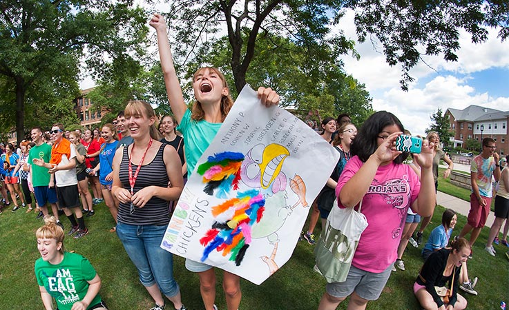 A group of students hold a sign and cheer during an activity at the Honors College orientation