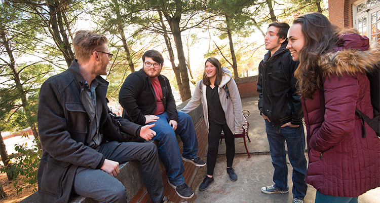 Four Honors College students standing and talking outside Whitmyre Hall