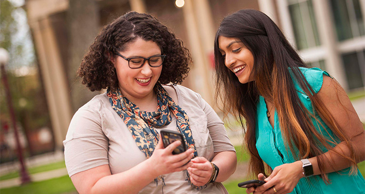 Two female honors college students looking at phone 