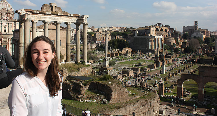 Honors student by ancient ruins while studying abroad