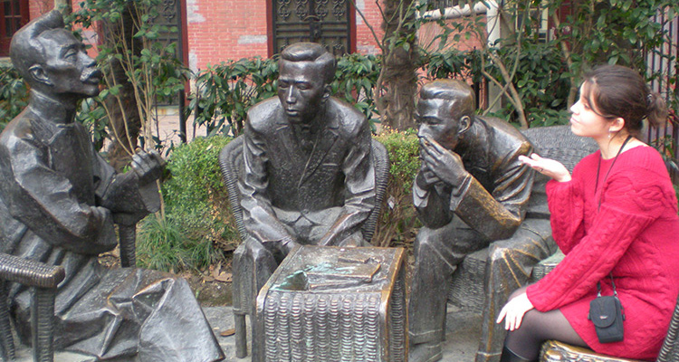 Gina Russo Tam sitting next to three statues 
