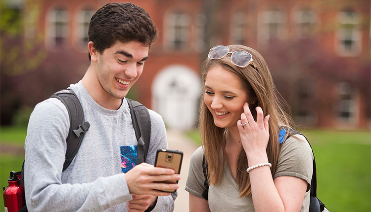 Honors college students laughing and looking at a cellphone 