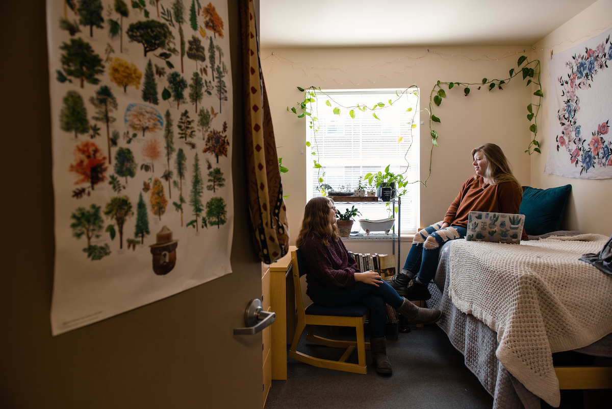 Two roommates chat in the bedroom of a two-person private suite. 